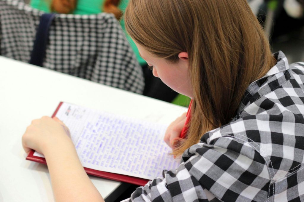 view from over a student's shoulder as she writes an essay